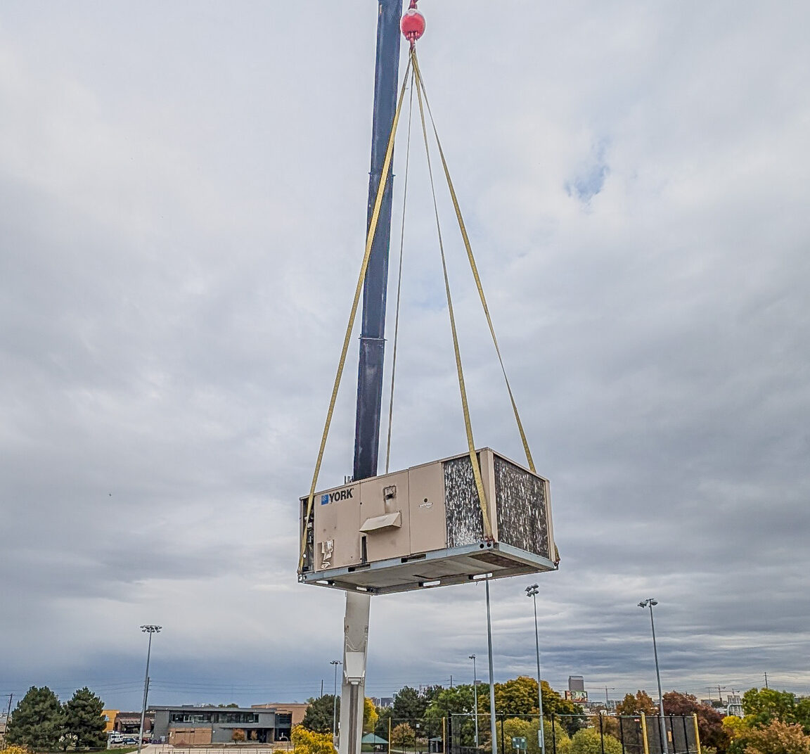 A Crane Lifting up a RTU on to a building in Denver Co